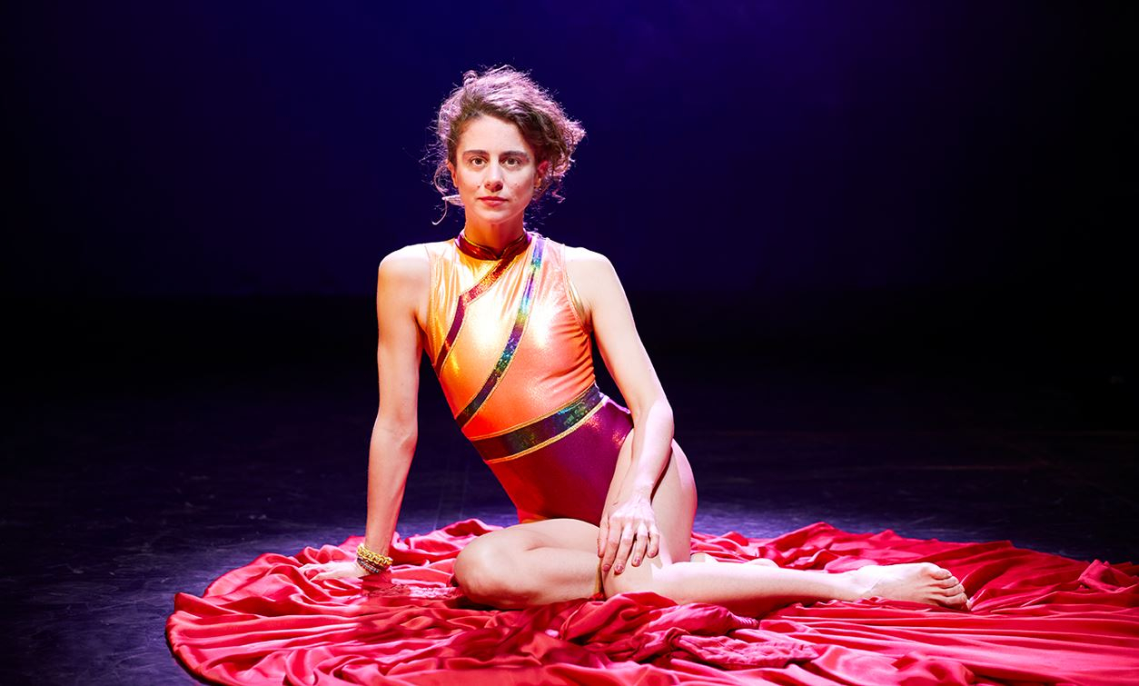 Une jeune fille assise sur une robe rose. Spectacle "Sous les paupières",