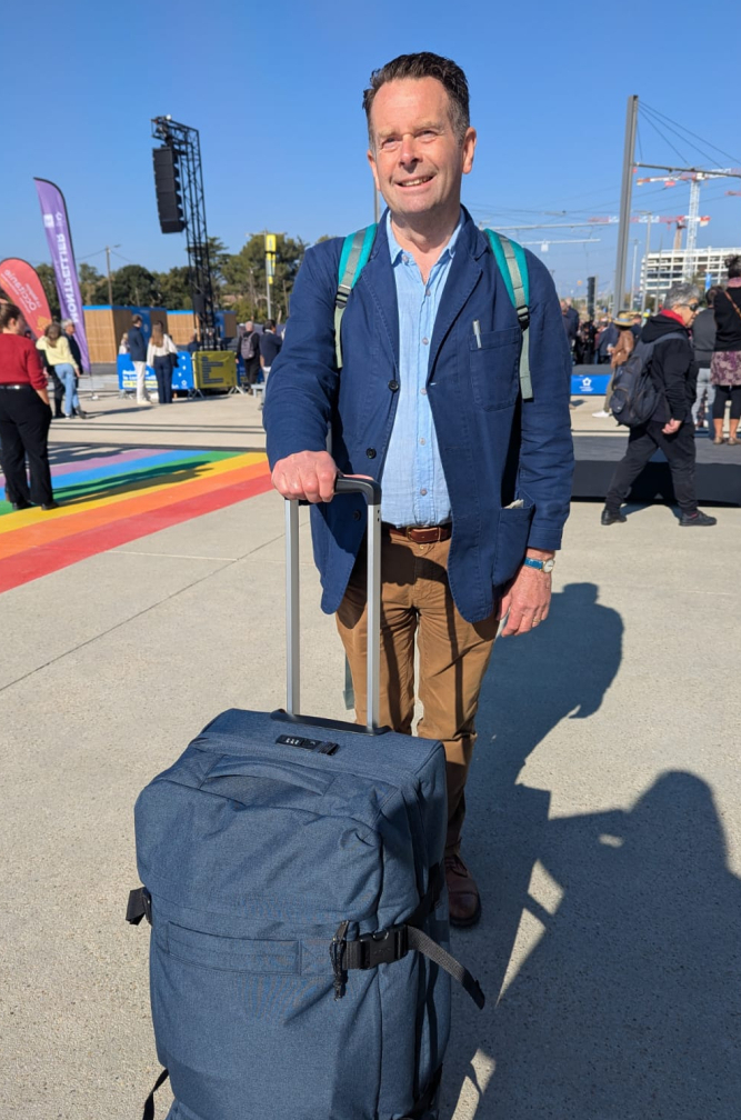 voyageur anglais sur la parvis de la gare rainbow flag personnes en arrière plan ciel 