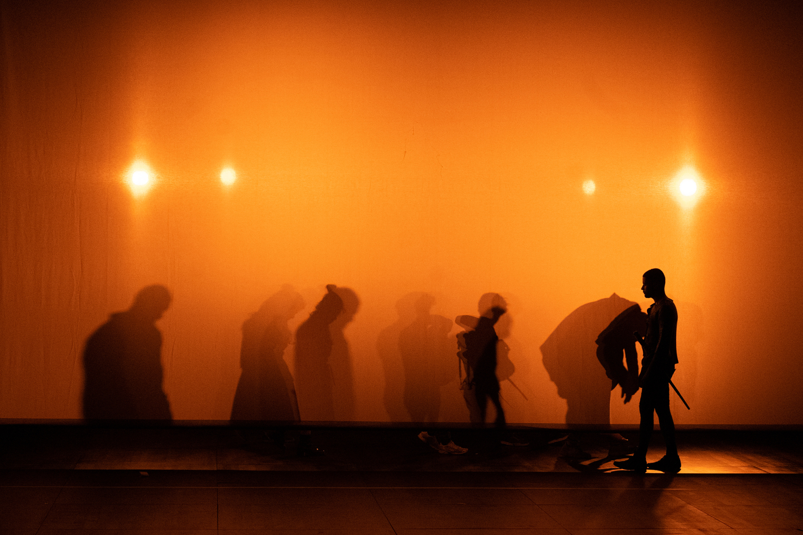 Silhouettes sur fonds orangé pour le spectacle de Wajdi Mouawad
