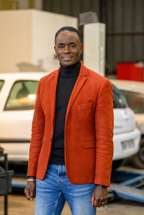 Cheikh Lo, directeur de Passerelles Synergies, voiture en arrière-plan